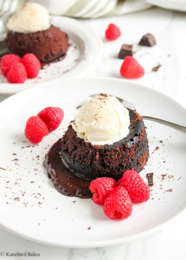 Molten Chocolate Lava Cakes for Two - 90 degree view with vanilla ice cream on top and raspberries around the sides, second cake in the background