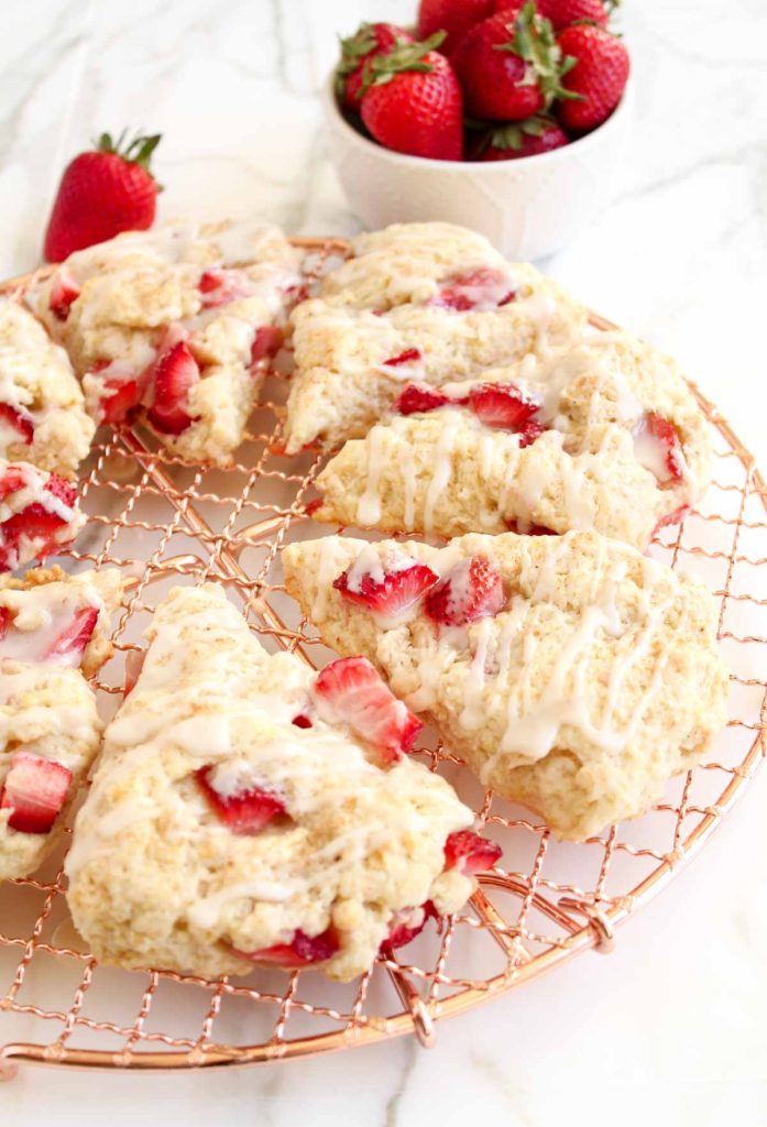 Strawberry scones on a copper rack against a white background