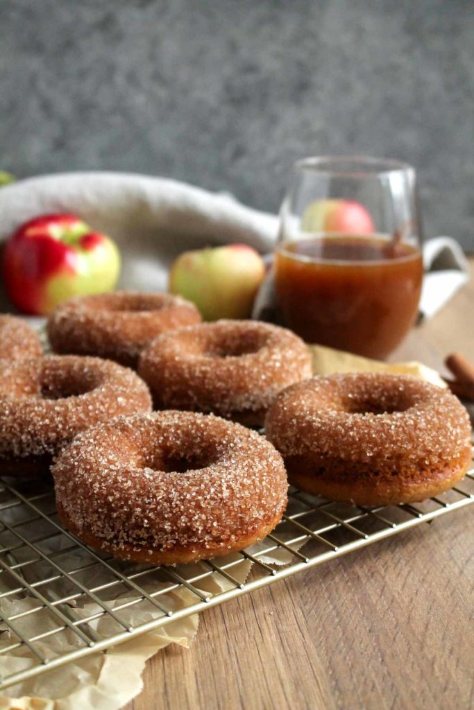A rack of donuts with apples in the background