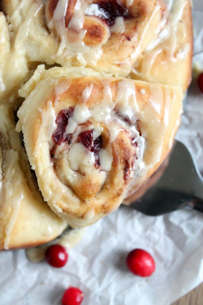 a spatula underneath a glazed cranberry roll