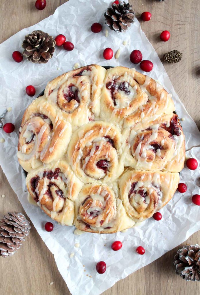 finished scrolls of dough on a table with cranberries scattered around the rolls