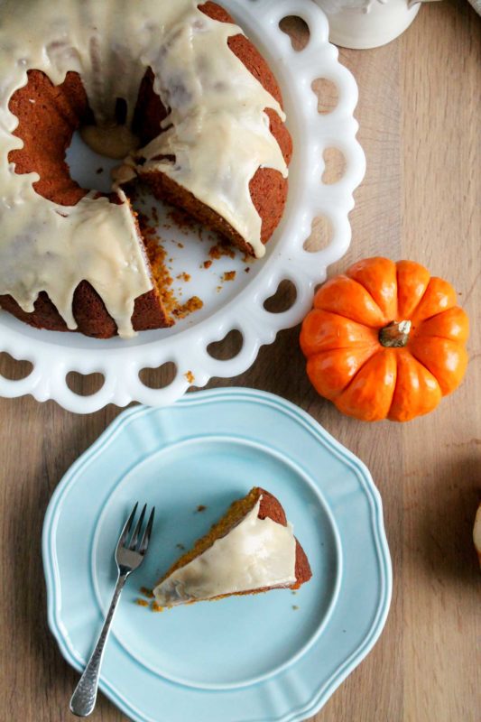 a slice of the brown butter glazed pumpkin spice bundt cake with the larger cake next to it