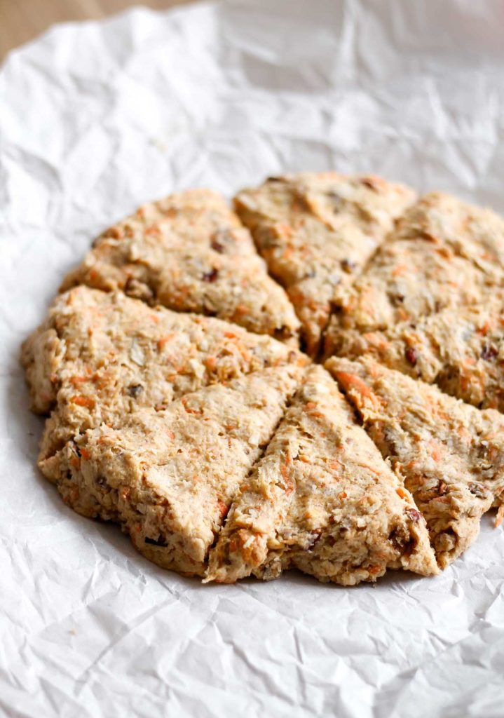 carrot scone dough arranged in a disk on a piece of parchment paper and cut into 8 wedges