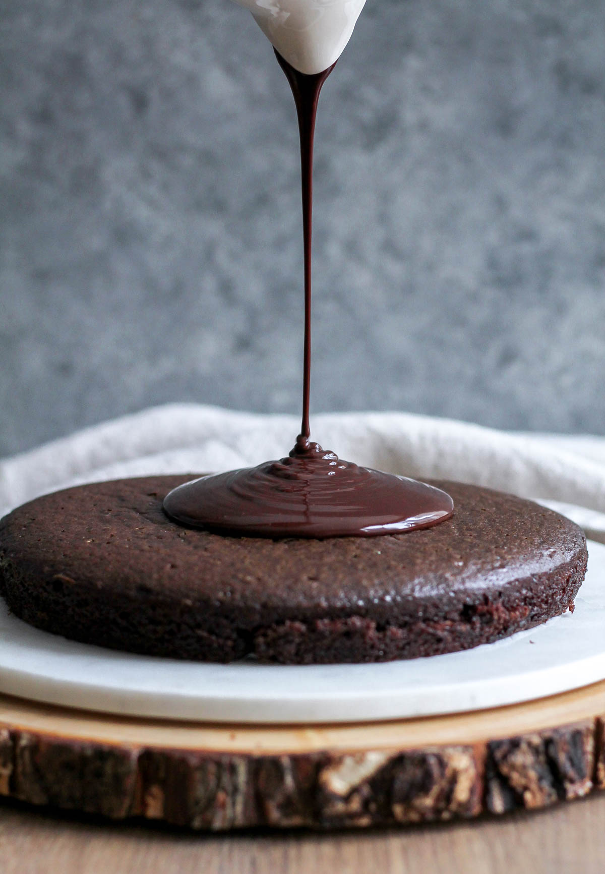 Glossy shiny ganache being poured over the cake