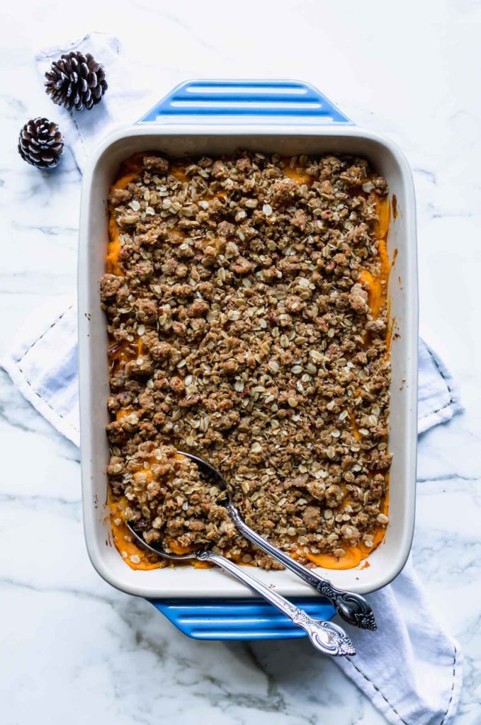 Light Sweet Potato Casserole made without eggs with Pecan Oat Topping - fully baked with serving spoons in the baking dish
