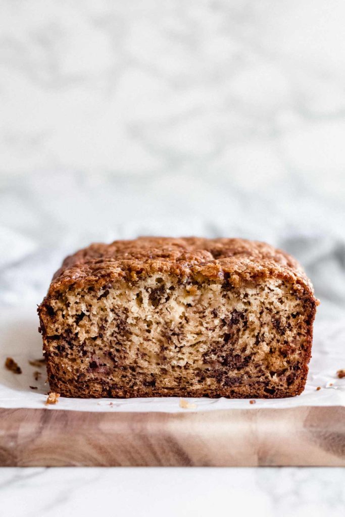 head-on view of the baked interior of this simple banana bread recipe, sitting on a wooden cutting board in front of a white background