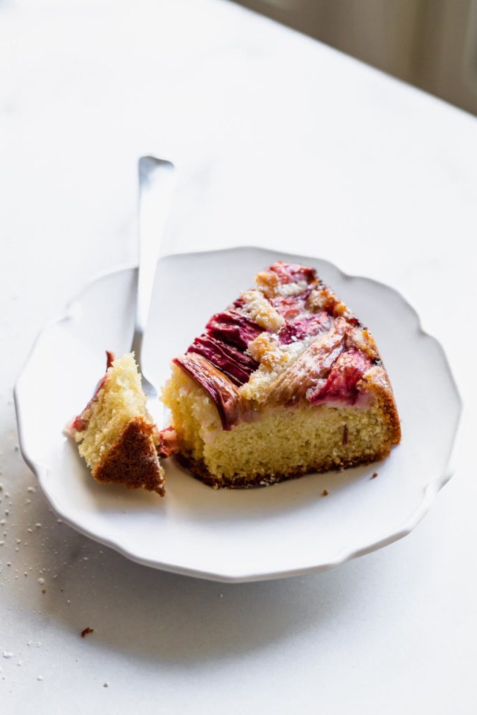 a slice of cake on a white plate with a fork having cut into it, set next to it on the plate