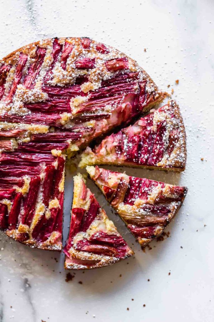 overhead view of the rhubarb cake on a white surface with 3 slices cut out