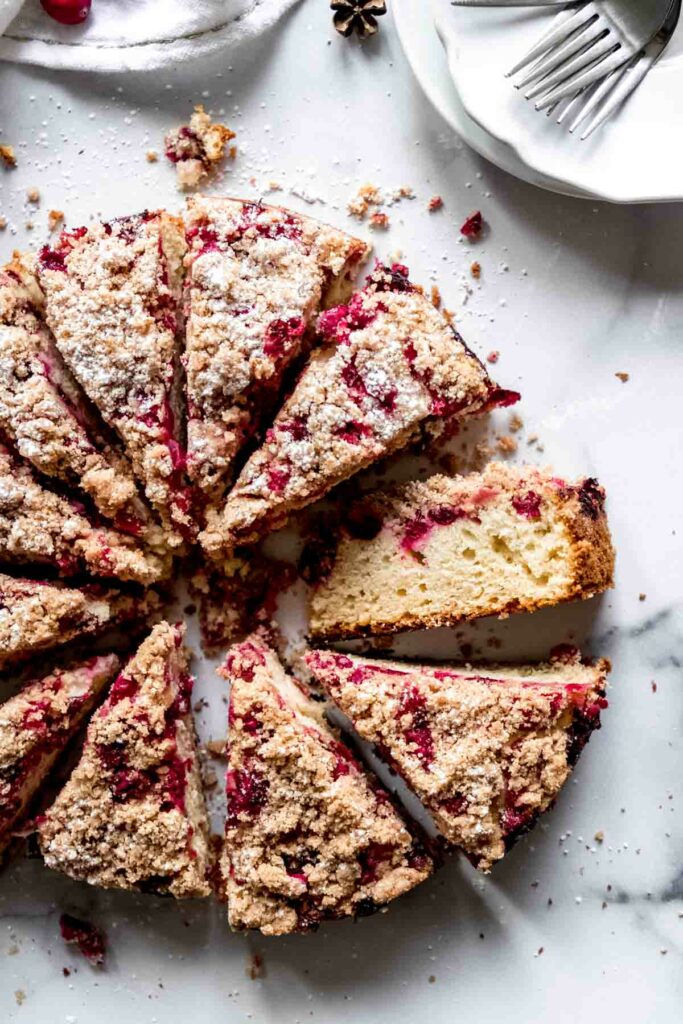 Cranberry coffee cake slices with cinnamon streusel topping arranged on a white surface