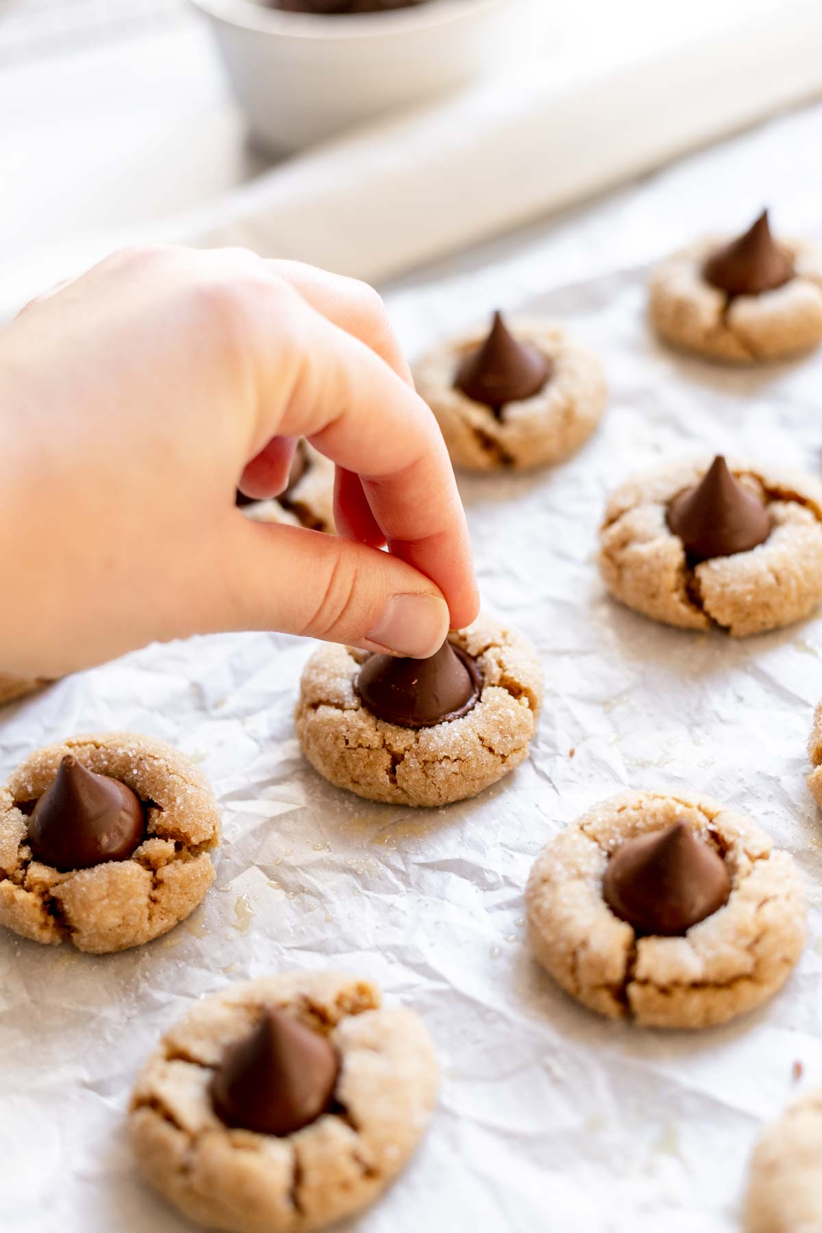 Pressing a kiss into the peanut butter blossom cookies