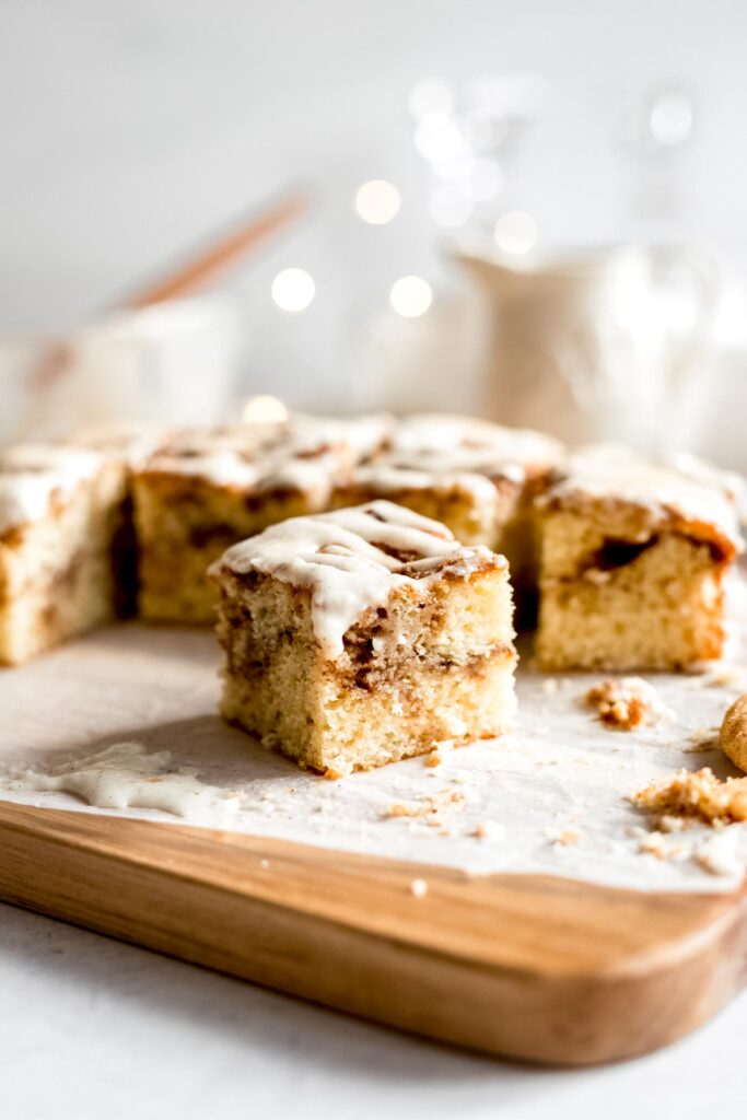 A cross section slice of Single Layer Snickerdoodle Cake with Cream Cheese Frosting on a wooden cutting board, clearly displaying the cinnamon swirls in the cake