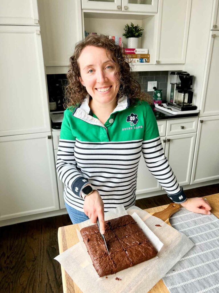 Katie in her kitchen cutting brownies
