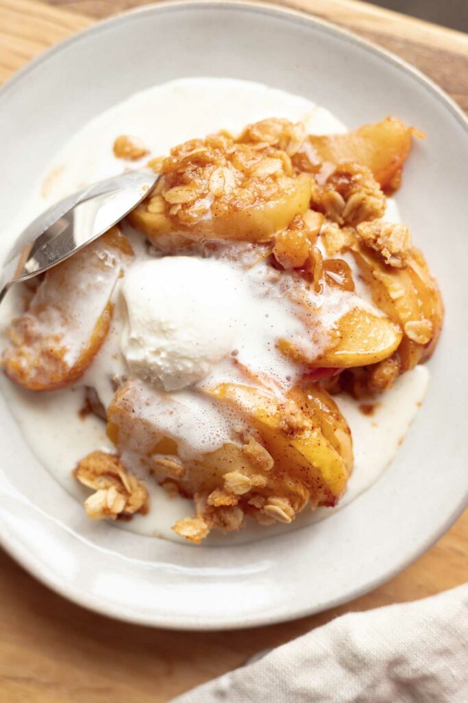 A bowl of apple crisp with oatmeal crumble topping and vanilla ice cream