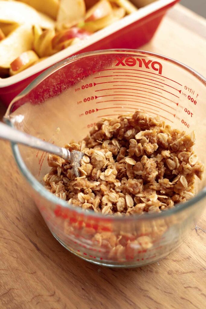 A bowl of oatmeal crumble topping mixture (made with melted butter) for apple crisp