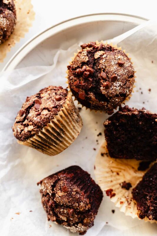 overhead view of a few double chocolate banana muffins in a basket, some unwrapped