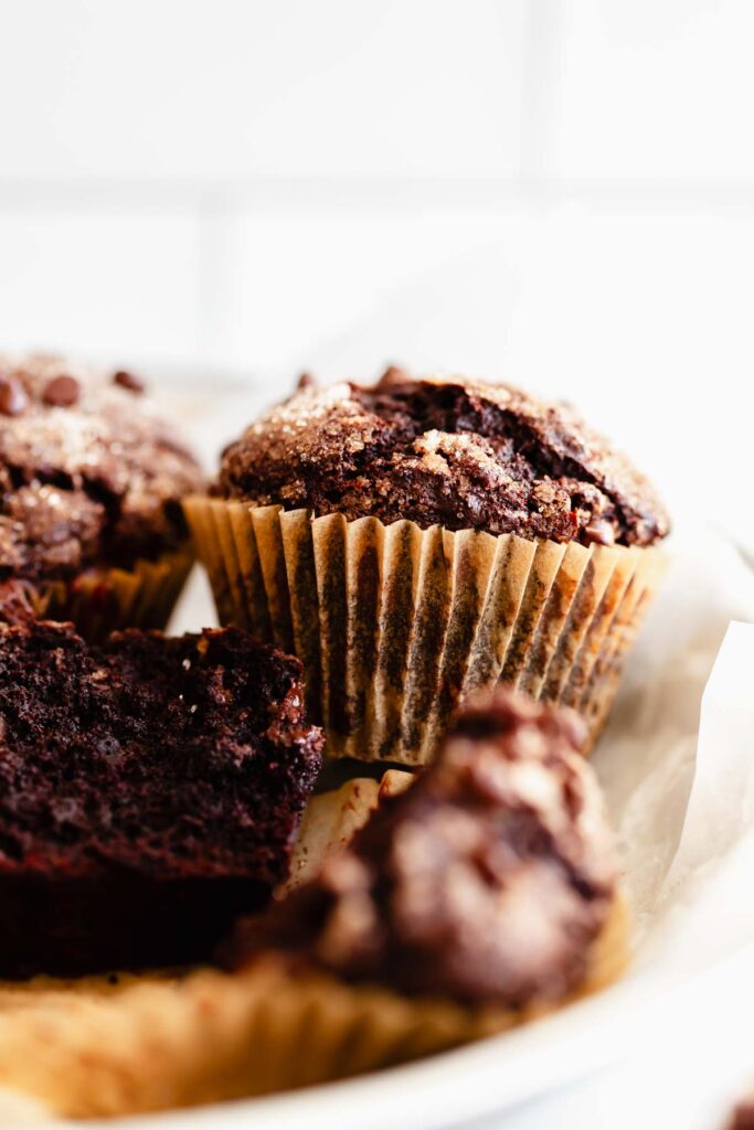 chocolate banana muffins in a small pile with close up of the tall bakery-style muffin top with chocolate chips