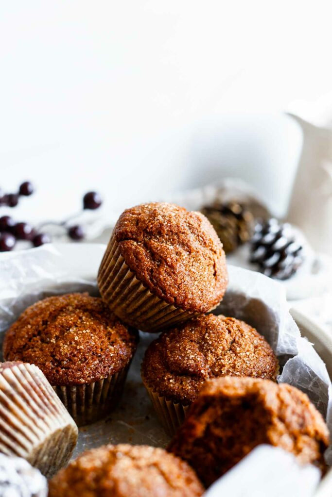 small batch molasses gingerbread muffins piled in front of a white background