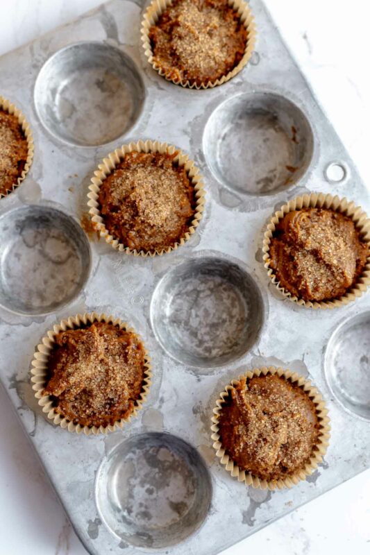 muffin batter scooped into six cups of a 12 cup muffin pan, topped with turbinado sugar