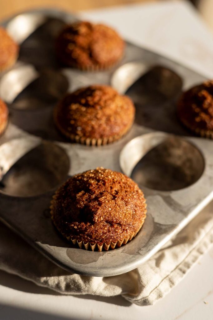 baked muffins in every other cup of muffin pan, sugar on top shining in afternoon sunlight