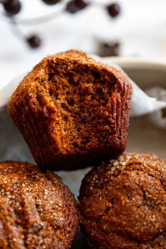 close up view of a gingerbread muffin with a bite taken out, showing the texture of the muffin crumb