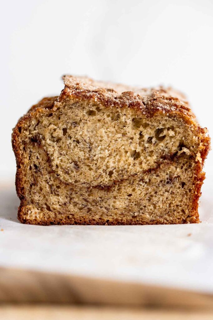 cross section of cinnamon swirl banana bread placed on a cutting board against a white background