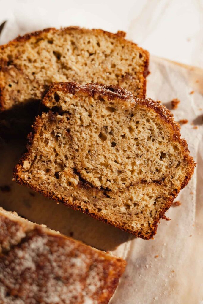 a piece of cinnamon swirl banana bread, just sliced and laying on a cutting board
