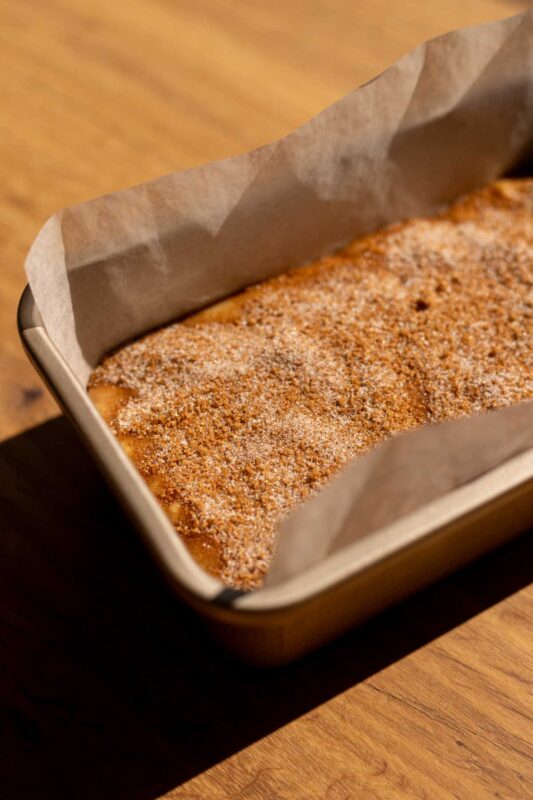batter in a loaf pan with cinnamon sugar on top