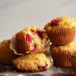 several cranberry orange muffins piled on top of each other on a muffin tin